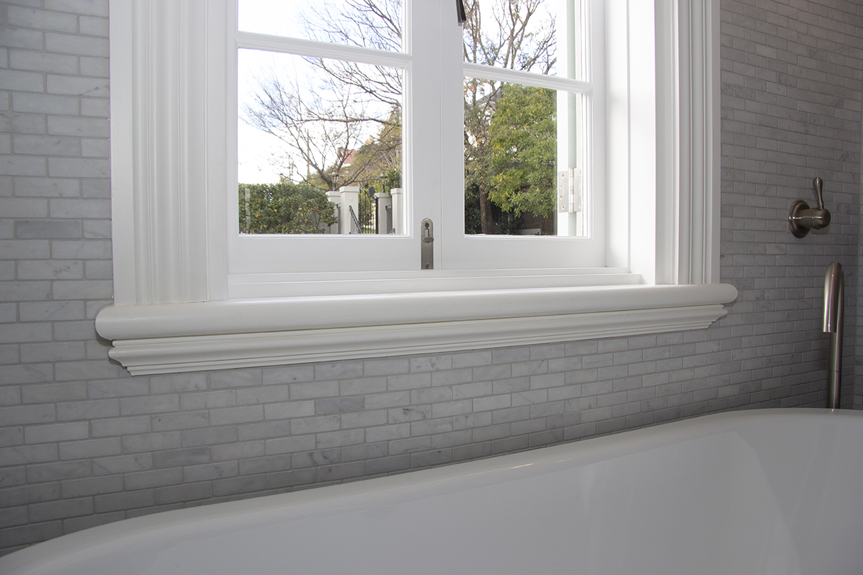 White timber sill nosing finishing a heritage casement window above a freestanding bath.