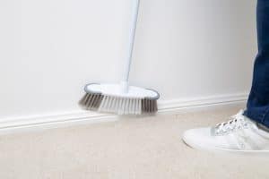 Cleaning skirting boards with a broom