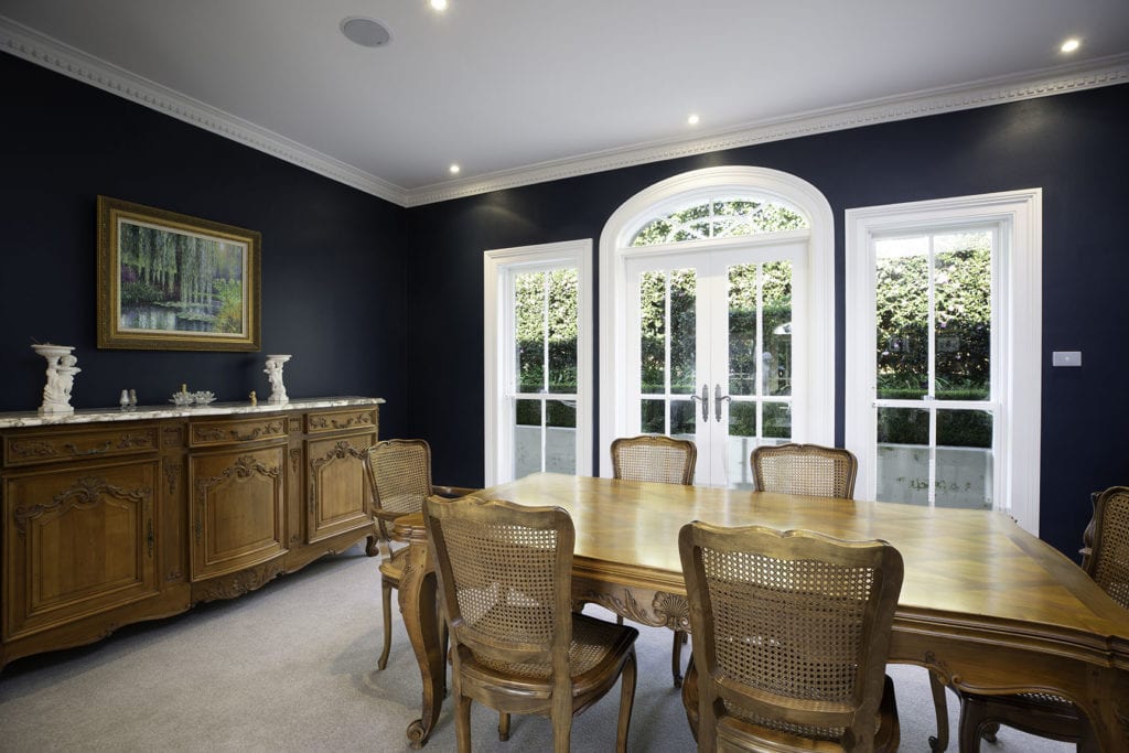Navy dining room with ornate mouldings and a curved French door