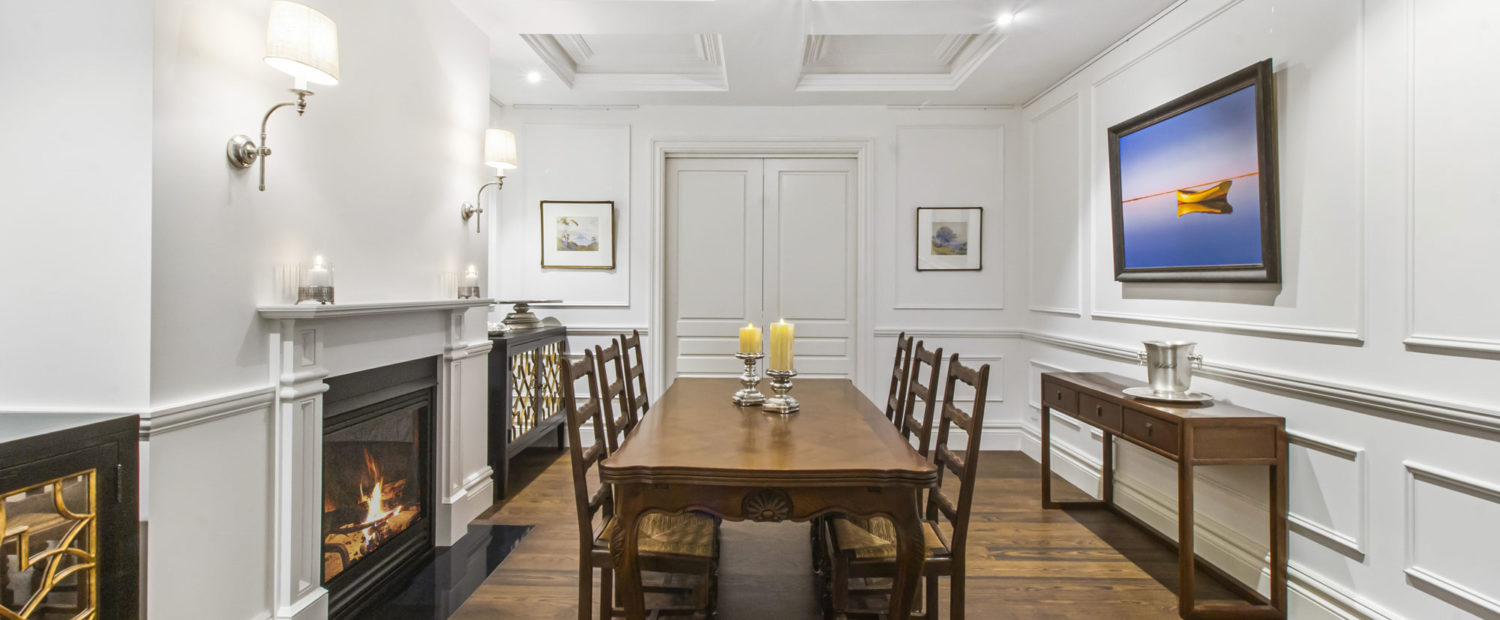 Formal dining room with floor-to-ceiling panelling, a coffered ceiling, fireplace and timber dining table