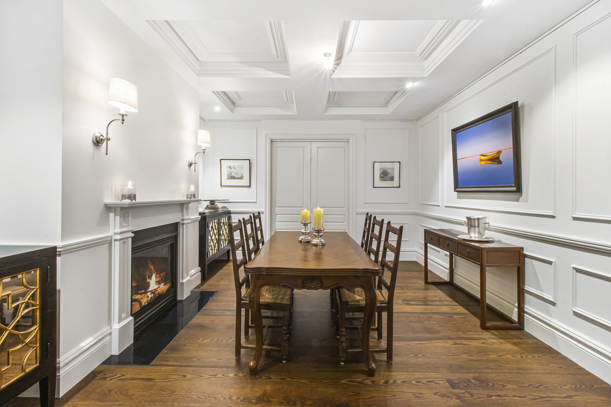 Formal dining room with floor-to-ceiling panelling, a coffered ceiling, fireplace and timber dining table