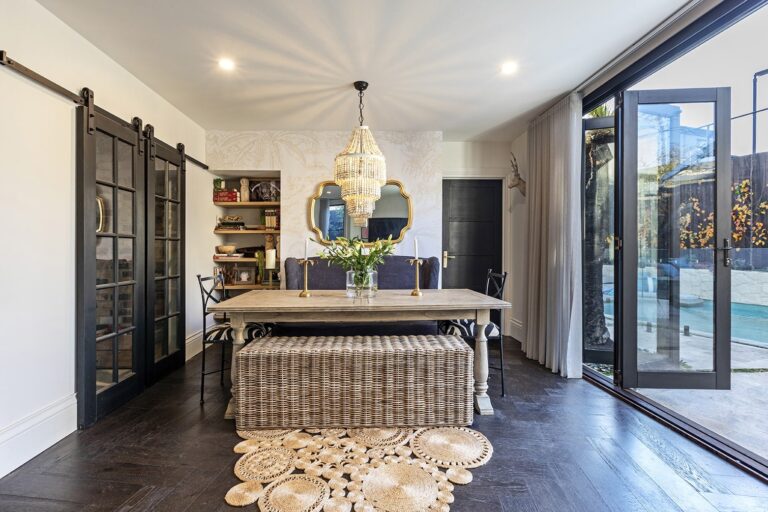 Transitional Modern Hamptons interior design with dark wood doors, wooden dining table, and gold accent chandelier