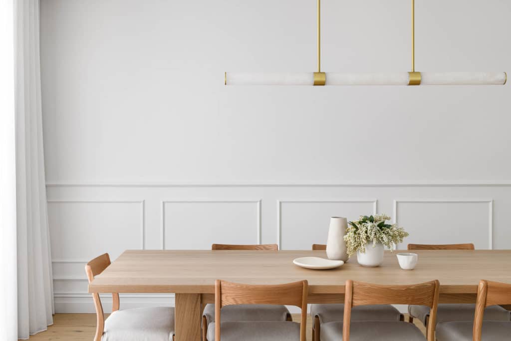 Slender white chair rail profile with matching wainscoting panels in a contemporary dining room, painted tone-on-tone