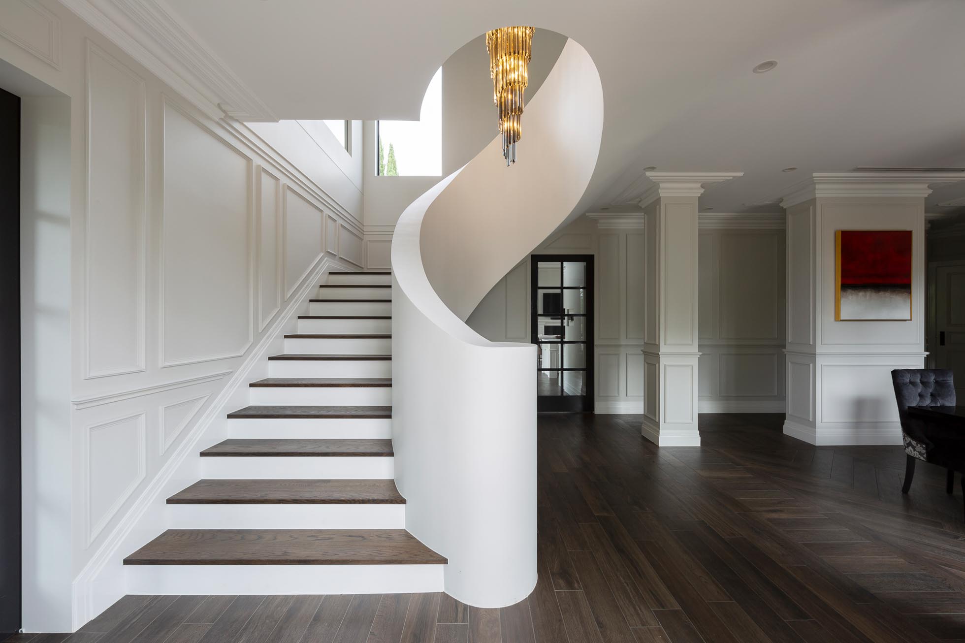 Grand staircase with curved white balustrade and classic wall panelling throughout