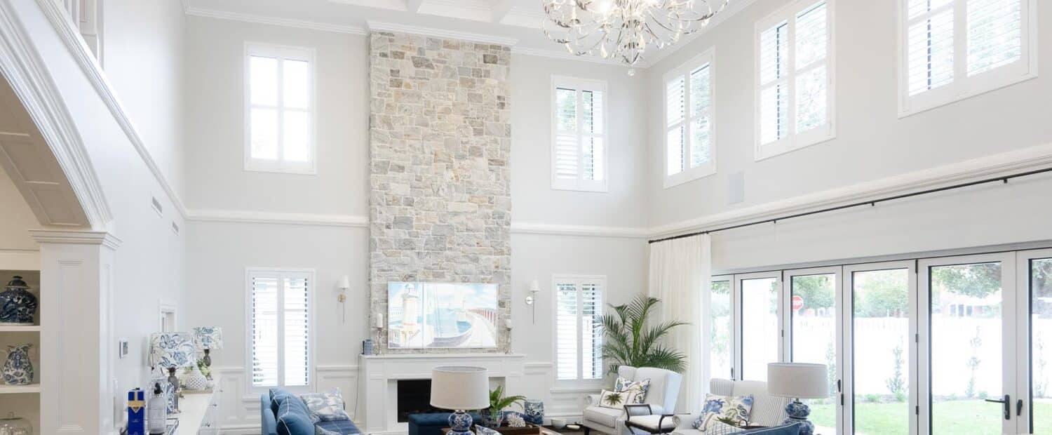 Modern Hamptons-style Indah Island Coolbinia large, open plan living space with high ceilings, grey stone accent wall, and feature chandelier
