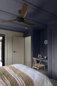 A bedroom with dark blue walls and ceiling