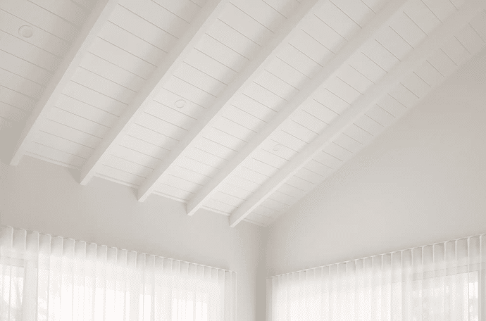 Serene living room with a white VJ-style panel pitched ceiling and exposed beams
