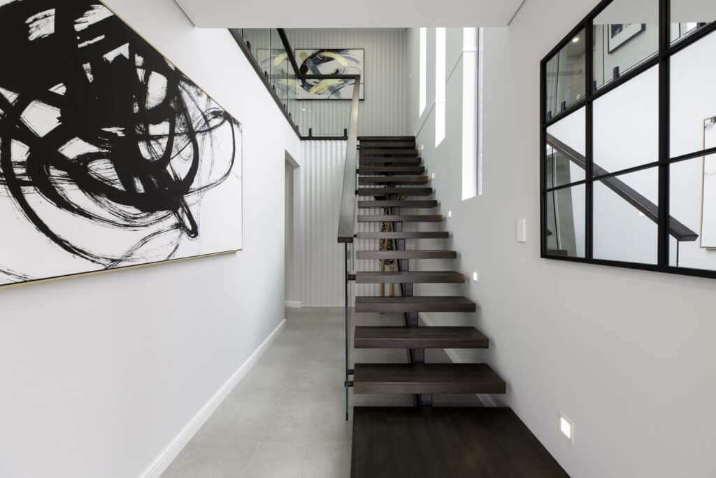 Modern Art Deco-style hallway featuring floating stairs in dark wood and abstract black and white wall art