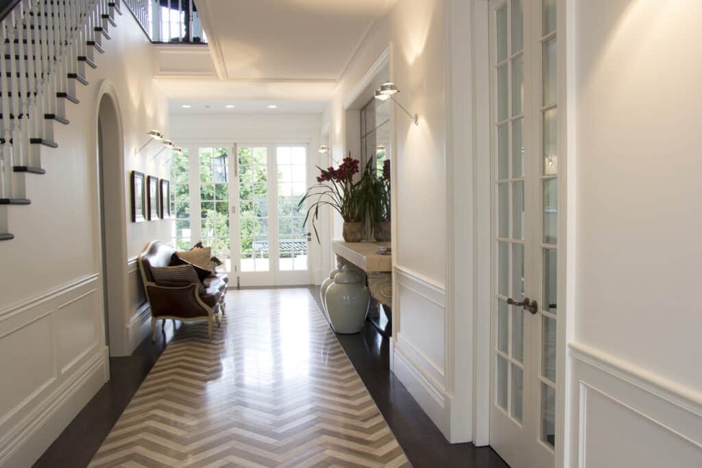 Elegant Georgian-style entranceway with herringbone flooring, white wall panelling, and a stylish waiting seat