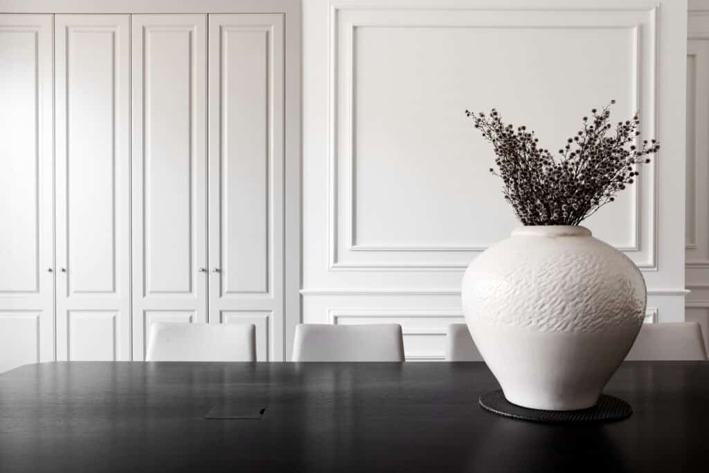 French Parisian-style tall cabinetry with black kitchen countertop and large white vase in the foreground