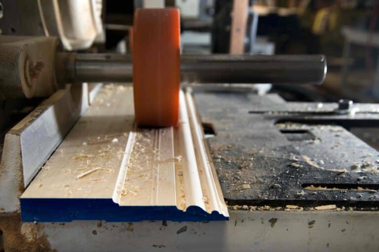 Close up shot of a workshop with a piece of timber moulding being shaped by a machine