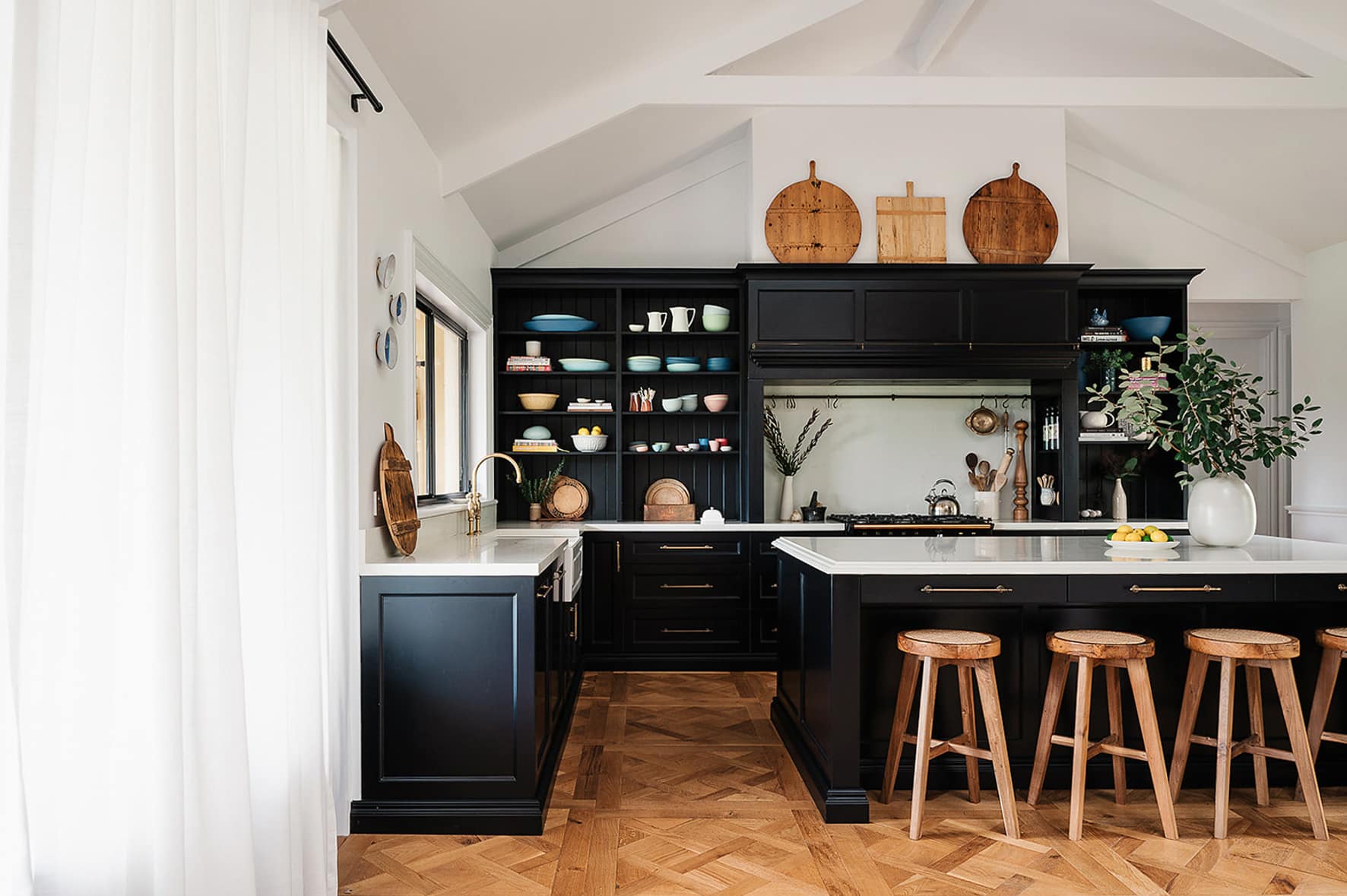 Classic black kitchen featuring decorative timber mouldings on cabinetry, detailed skirting boards, and panelled joinery in a contemporary Australian home