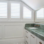 Bathroom with wainscoting, plantation shutters, and green marble vanity—Intrim mouldings add texture and refinement to this private retreat.