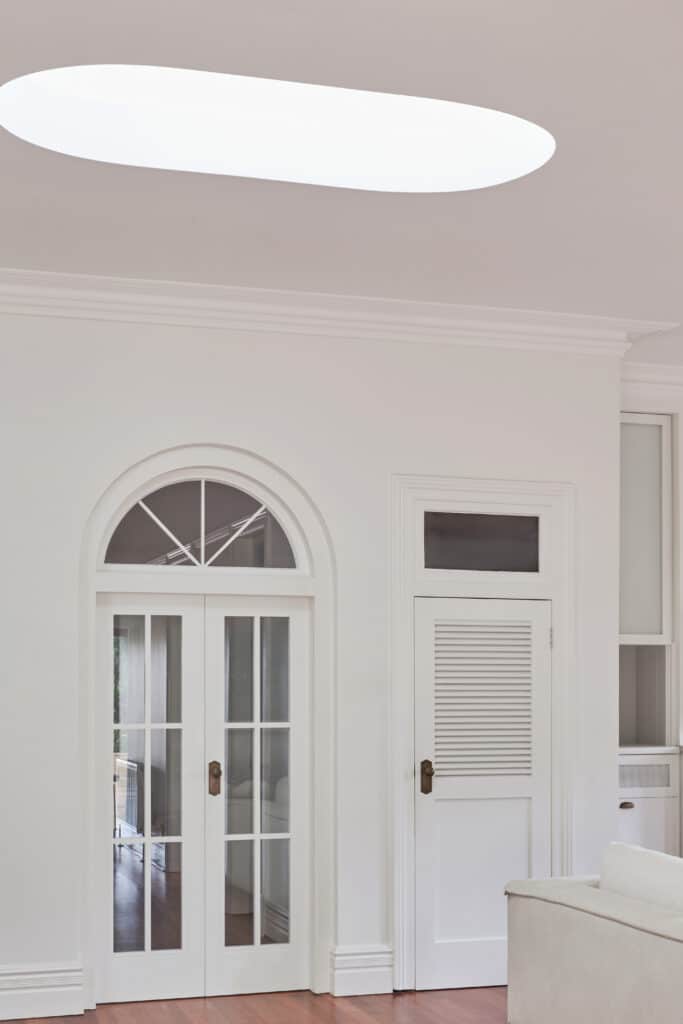 Bright transitional space featuring arched double glass doors, skylight-enhanced natural lighting, and refined Intrim mouldings framing ceiling and doorways—ideal for heritage-inspired interiors.