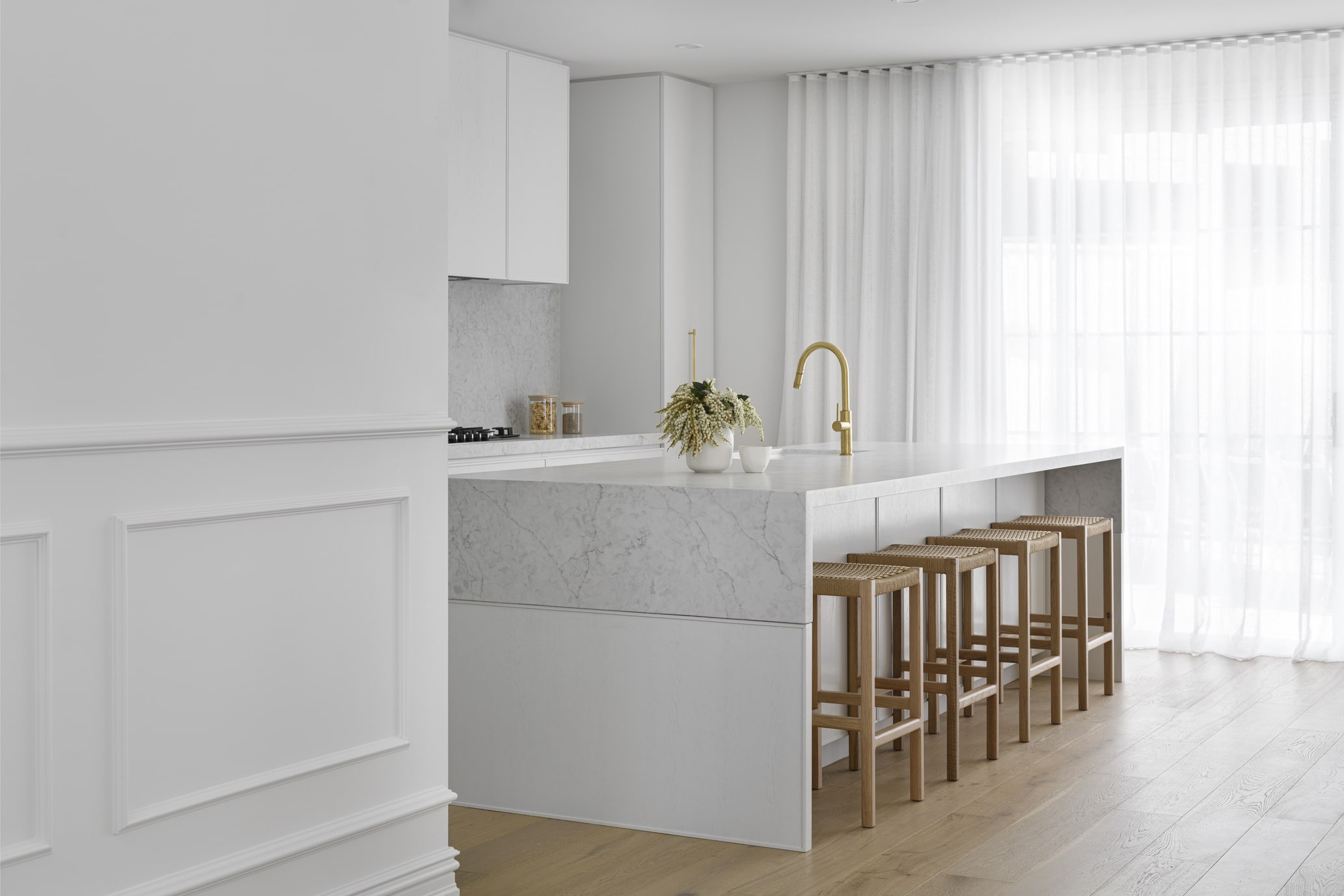 Modern white kitchen wall with chair rail and inlay mould panel detailing alongside a marble waterfall island.