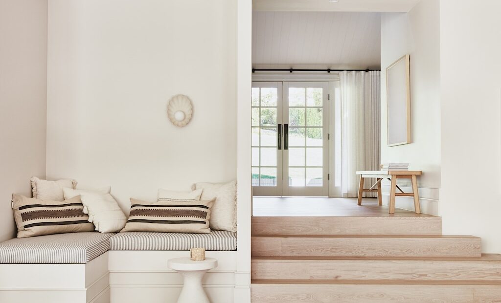 Contemporary interior design showcasing light wooden steps, a cosy corner with striped cushions, and airy double doors