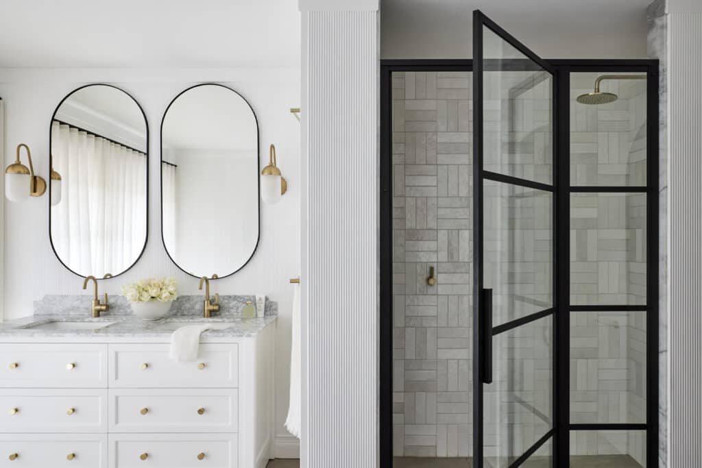 Modern bathroom with fluted wall panelling and decorative column detail, adding texture beside a double vanity and glass shower.