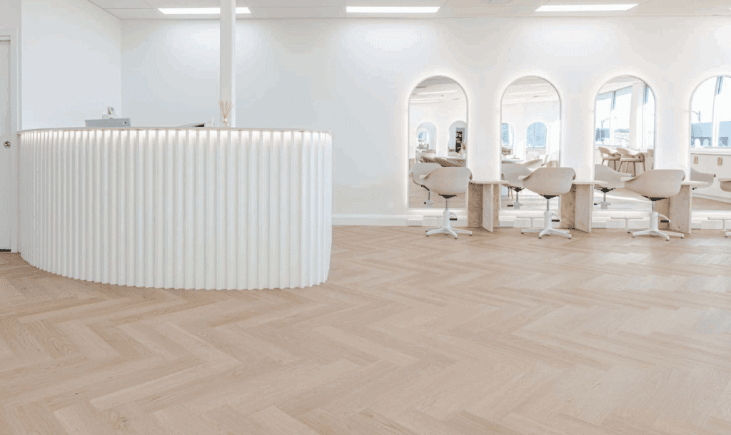 Minimalist salon interior featuring a statement reception desk crafted with white concave moulding