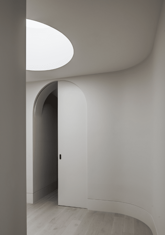 Curved skirting board used throughout a contemporary, rounded hallways with and arched doorway and circular skylight