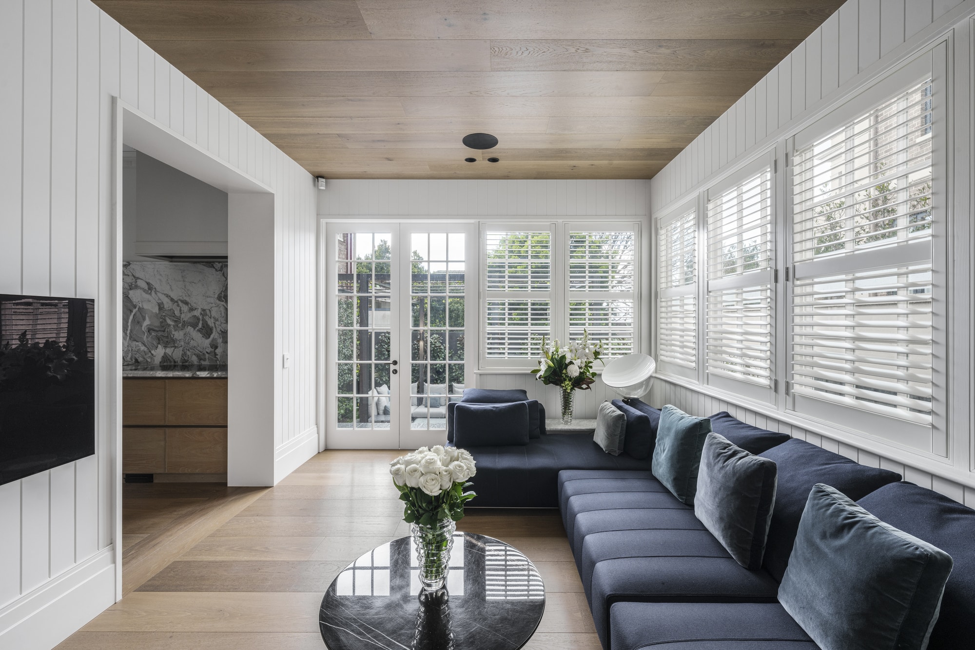 Living room featuring vertical wall panelling, detailed timber skirting boards and window architraves, creating a refined coastal-style Australian interior.