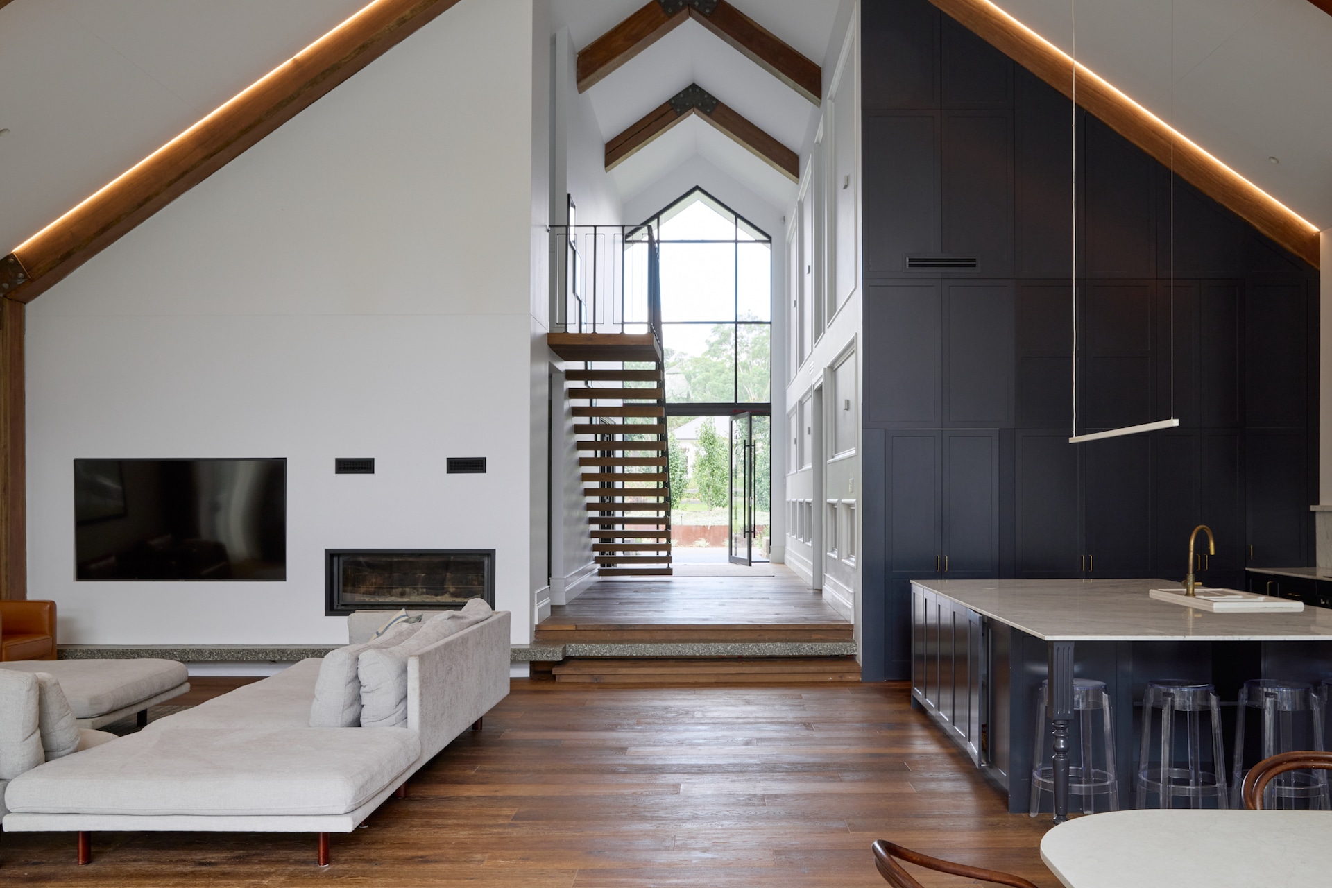 farmhouse: Modern farmhouse interior with vaulted ceilings, exposed timber beams, detailed wall panelling, and statement timber skirting and architraves enhancing architectural scale.