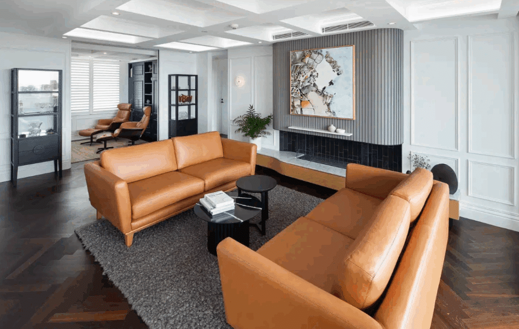 Modern Contemporary living room with eye-catching vertical wall panelling, dark herringbone wood flooring, and luxurious brown leather sofas.