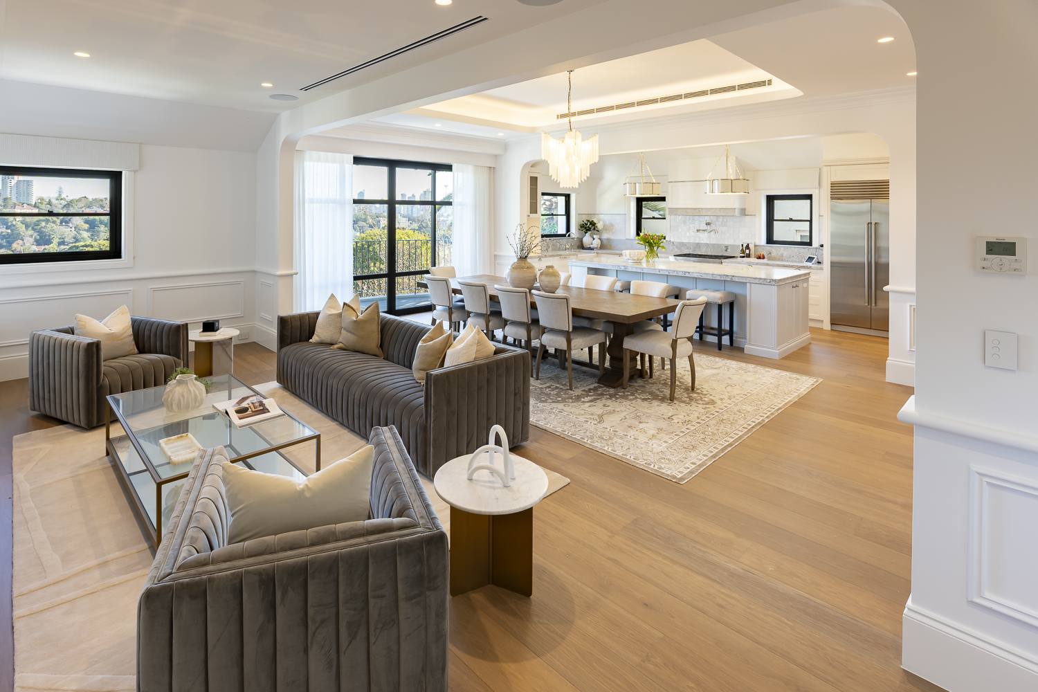 Open-plan living and dining area featuring decorative wall panelling, detailed timber skirting boards, and classic cornice mouldings in a contemporary Australian home
