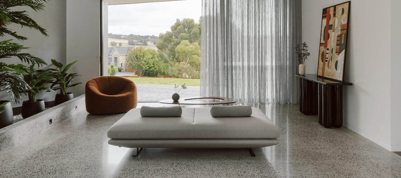 Contemporary Australian living space with terrazzo floors, floor-to-ceiling glazing, sheer curtains, and clean Shadowline skirting detail.