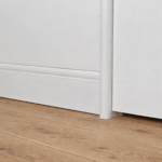 A close up shot of curved flush finish skirting board painted in white against a timber floor.