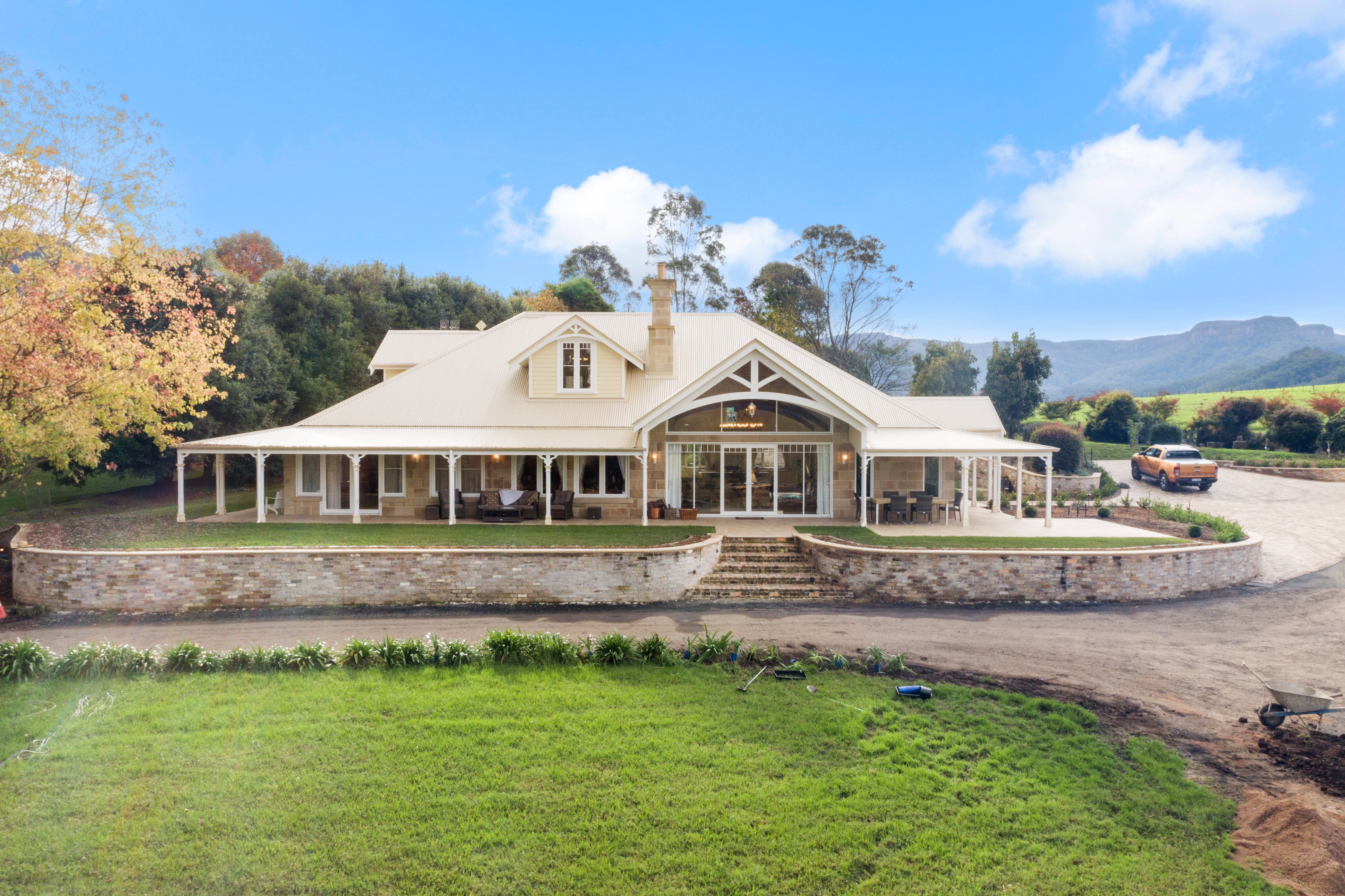 Federation-style Australian homestead with wraparound verandah, decorative timber fretwork brackets, gabled roof and central arched window.