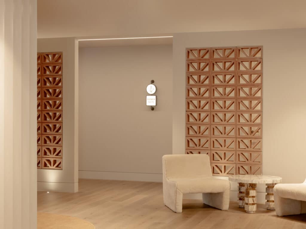 Lounge area at Zagame's Place Hawthorn featuring decorative terracotta breeze block screen panels, a cream boucle armchair, stone pedestal side table, and Intrim SK800B Shadowline flush skirting along light timber floors