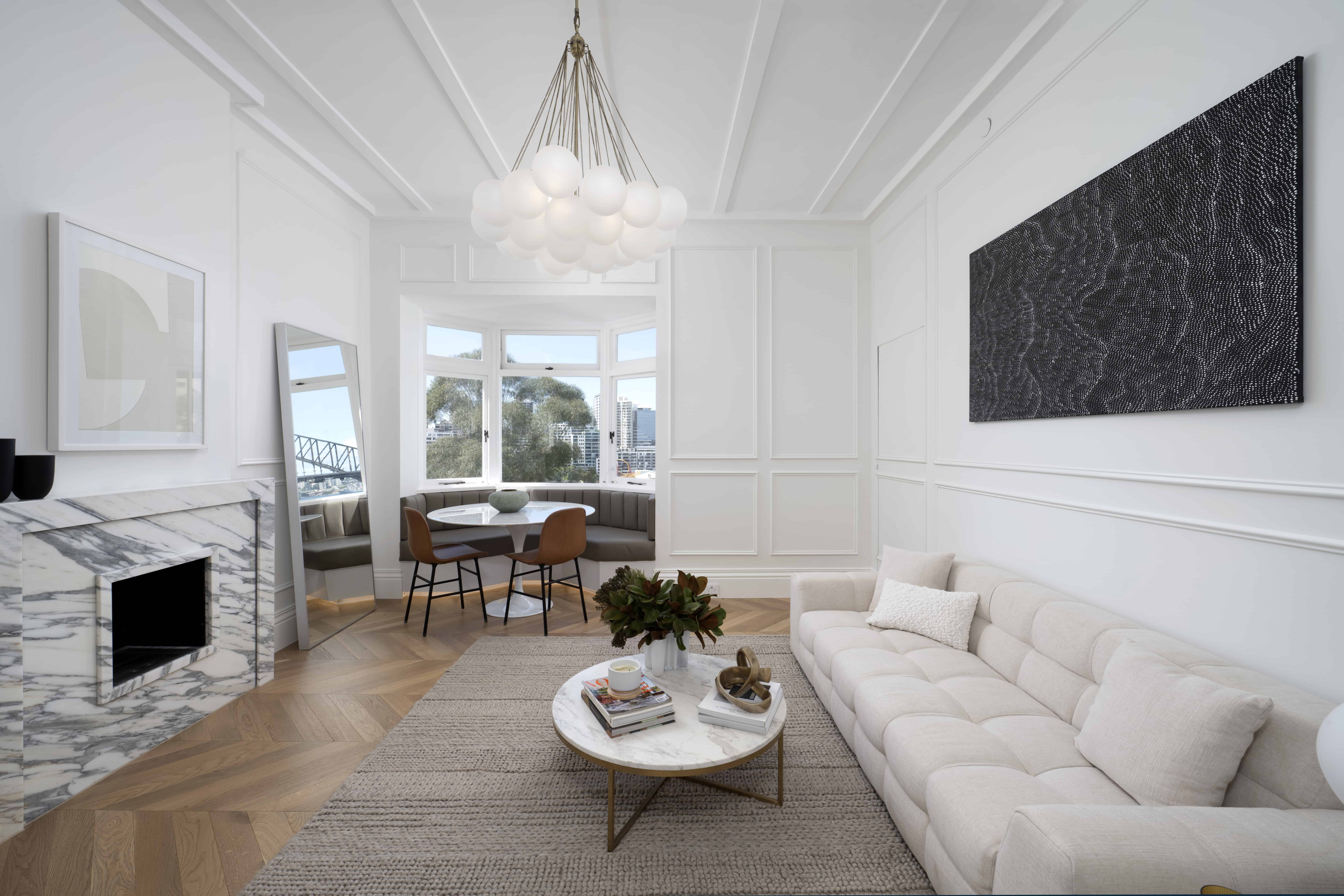 Contemporary Sydney harbourside apartment interior with full-height wall panelling, chair rail, stepped cornice, and chevron oak parquet flooring.
