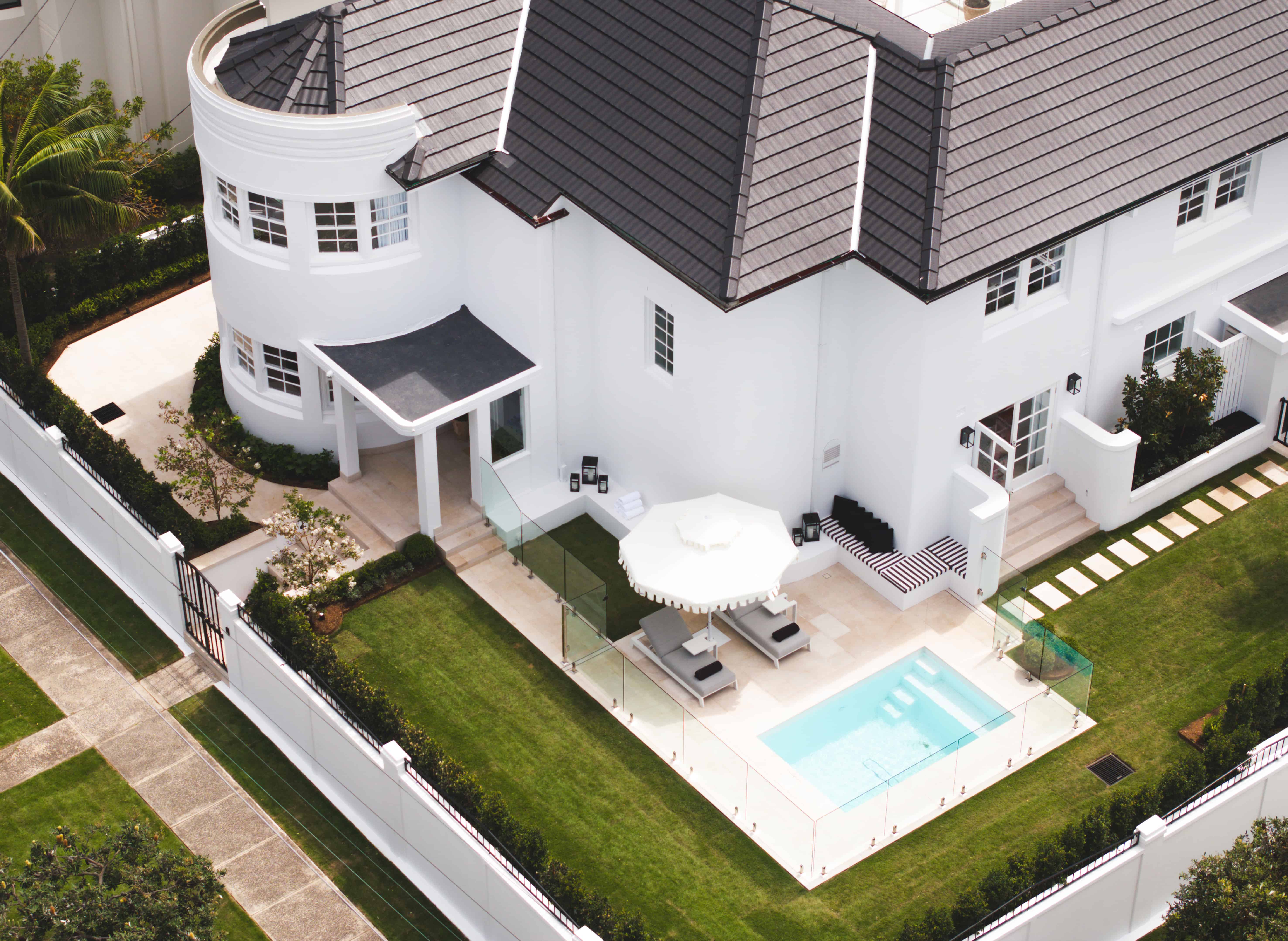 Australian Art Deco home exterior with curved white-rendered façade, multi-pane steel-framed windows, geometric tiled roof, and streamlined porch canopy.
