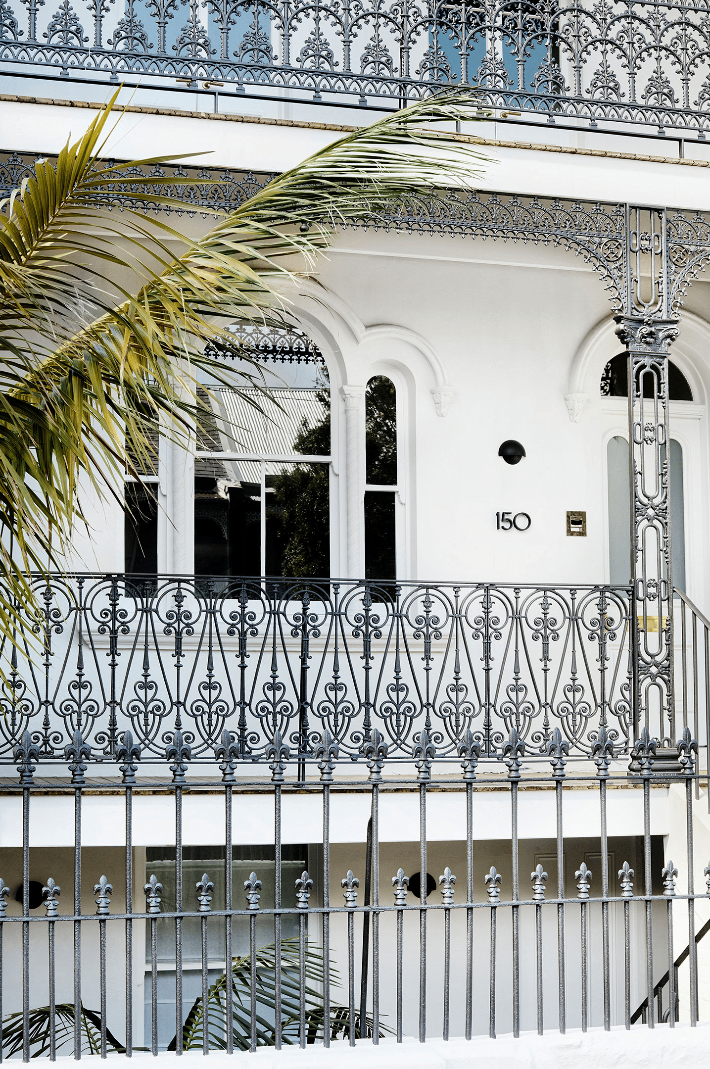 Restored Victorian Filigree terrace house with ornate cast-iron lacework verandah, arched windows and decorative ironwork balustrades.