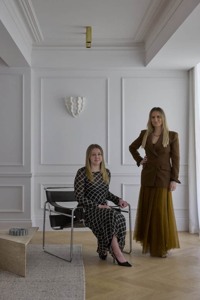 Bianca Fraser, Director and Interior Designer at The Unlisted Collective, standing beside a seated colleague in a white-panelled room finished with Intrim inlay mould and chair rail.