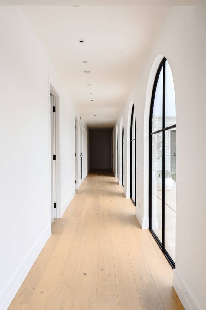 Bright farmhouse hallway featuring arched black-framed windows, oak flooring and Intrim SK1474 skirting.
