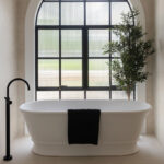 Freestanding bath positioned beneath a statement arched window with custom curved Intrim architrave, creating a refined transitional farmhouse bathroom.