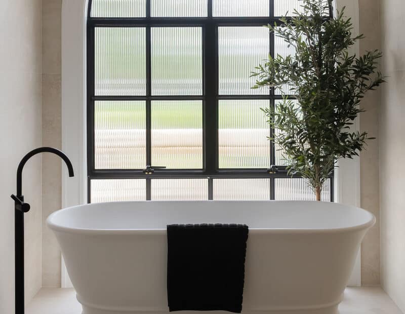 Freestanding bath positioned beneath a statement arched window with custom curved Intrim architrave, creating a refined transitional farmhouse bathroom.