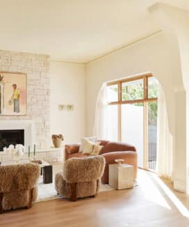 Elegant living room at Maison Soleil featuring Intrim SK945B skirting boards and architraves, a stone fireplace and arched openings in a refined French Country interior.