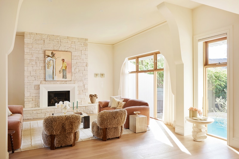 Elegant living room at Maison Soleil featuring Intrim SK945B skirting boards and architraves, a stone fireplace and arched openings in a refined French Country interior.