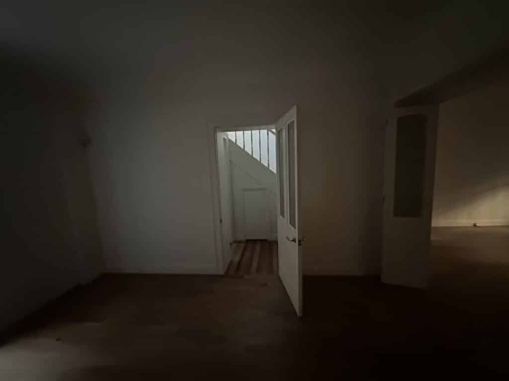 A dim, terrace basement with a glazed door opening to the staircase beyond.