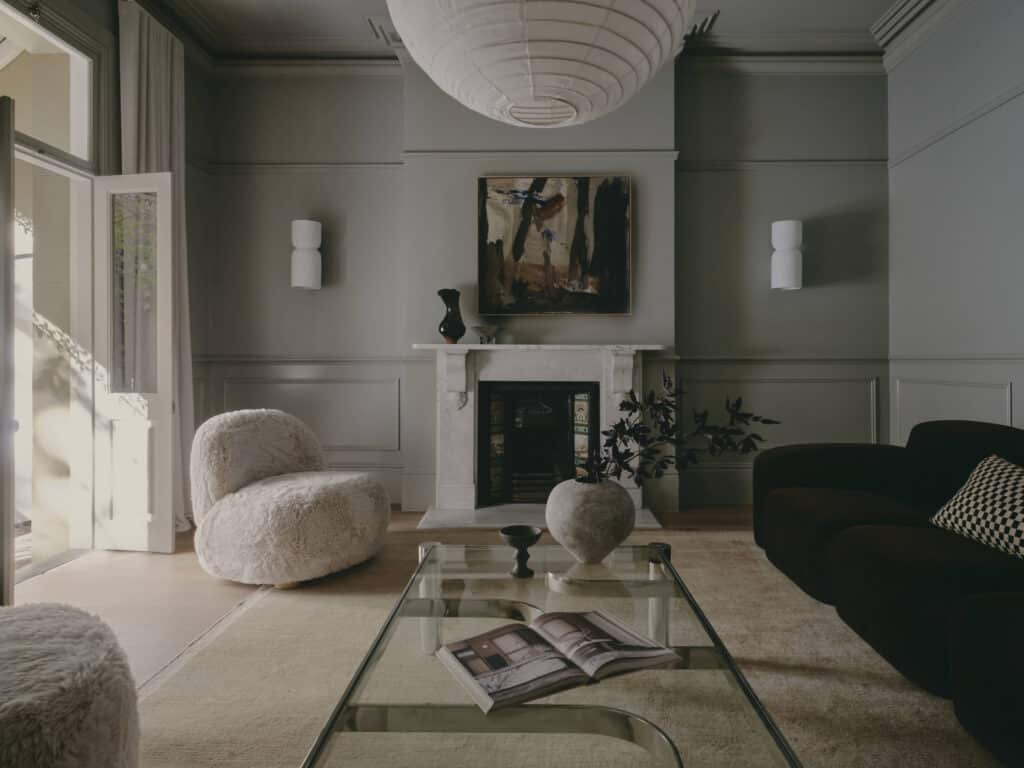 Formal terrace living room with green-grey panelled walls, a white marble fireplace, a paper pendant lantern and a French door open to the balcony.