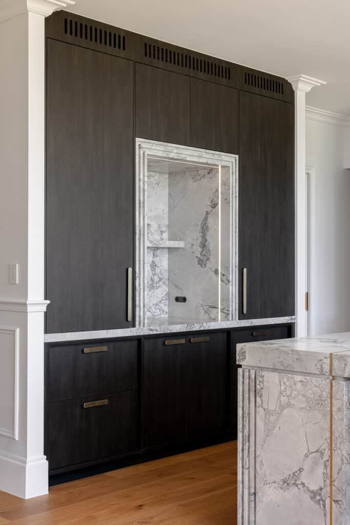 Custom dark timber joinery with marble-lined recess and contemporary farmhouse kitchen detailing